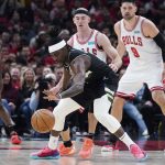 
              Milwaukee Bucks guard Jrue Holiday, center front, controls the ball against Chicago Bulls guard Alex Caruso, center back, during the first half of Game 3 of a first-round NBA basketball playoff series Friday, April 22, 2022, in Chicago. (AP Photo/Nam Y. Huh)
            