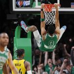 
              Boston Celtics' Jayson Tatum (0) hangs from the rim after a dunk during the second half of the team's NBA basketball game against the Indiana Pacers, Friday, April 1, 2022, in Boston. (AP Photo/Michael Dwyer)
            