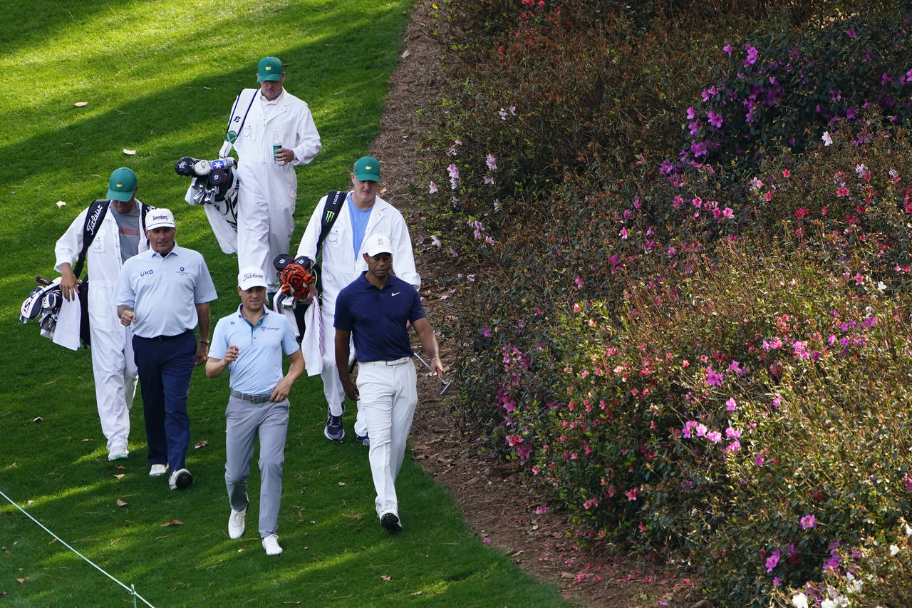 Fred Couples, left, Justin Thomas and Tiger Woods walk down the sixth fairway during a practice rou...