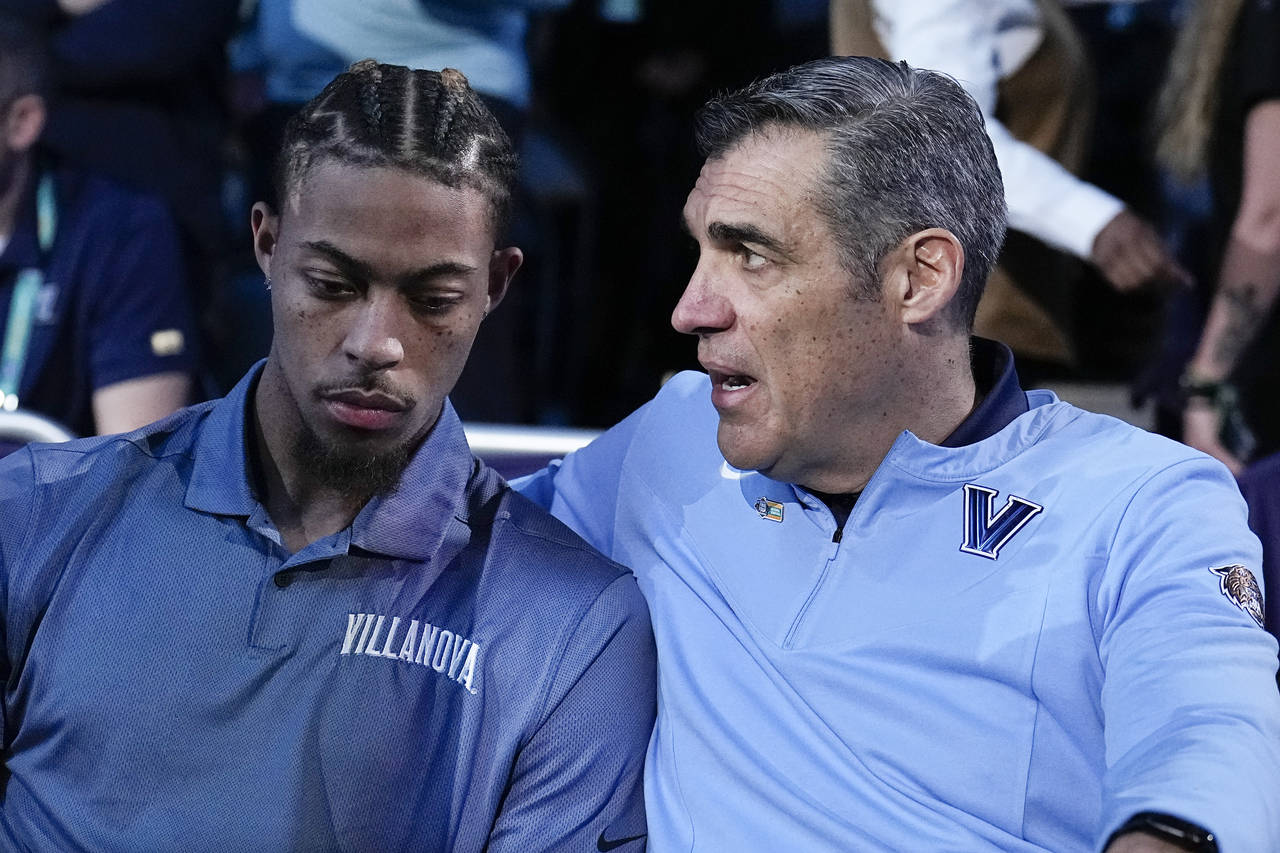 Injured Villanova guard Justin Moore sits with head coach Jay Wright before a college basketball ga...