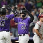 
              Colorado Rockies' C.J. Cron, center, is congratulated, as he crosses home plate after hitting a three-run home run, by Charlie Blackmon, left, as Philadelphia Phillies catcher J.T. Realmuto waits during the seventh inning of a baseball game Tuesday, April 19, 2022, in Denver. (AP Photo/David Zalubowski)
            