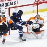 
              Winnipeg Jets' Brenden Dillon (5) attempts to put the puck past Philadelphia Flyers goaltender Felix Sandstrom (32) as Morgan Frost (48) defends during the first period of an NHL hockey game, Wednesday, April 27, 2022 in Winnipeg, Manitoba. (John Woods/The Canadian Press via AP)
            