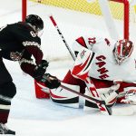 
              Carolina Hurricanes goaltender Antti Raanta (32) stops a shot by Arizona Coyotes defenseman J.J. Moser, left, during the first period of an NHL hockey game Monday, April 18, 2022, in Glendale, Ariz. (AP Photo/Ross D. Franklin)
            