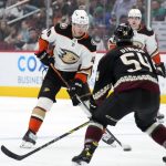 
              Anaheim Ducks center Trevor Zegras (46) carries the puck in front of Arizona Coyotes defenseman Cam Dineen (54) during the first period of an NHL hockey game Friday, April 1, 2022, in Glendale, Ariz. (AP Photo/Rick Scuteri)
            