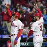 
              Philadelphia Phillies' J.T. Realmuto, left, and Bryce Harper gesture to second base as they celebrate after scoring on a double hit by Kyle Schwarber off Colorado Rockies starting pitcher Kyle Freeland during the third inning of a baseball game, Monday, April 25, 2022, in Philadelphia. (AP Photo/Derik Hamilton)
            