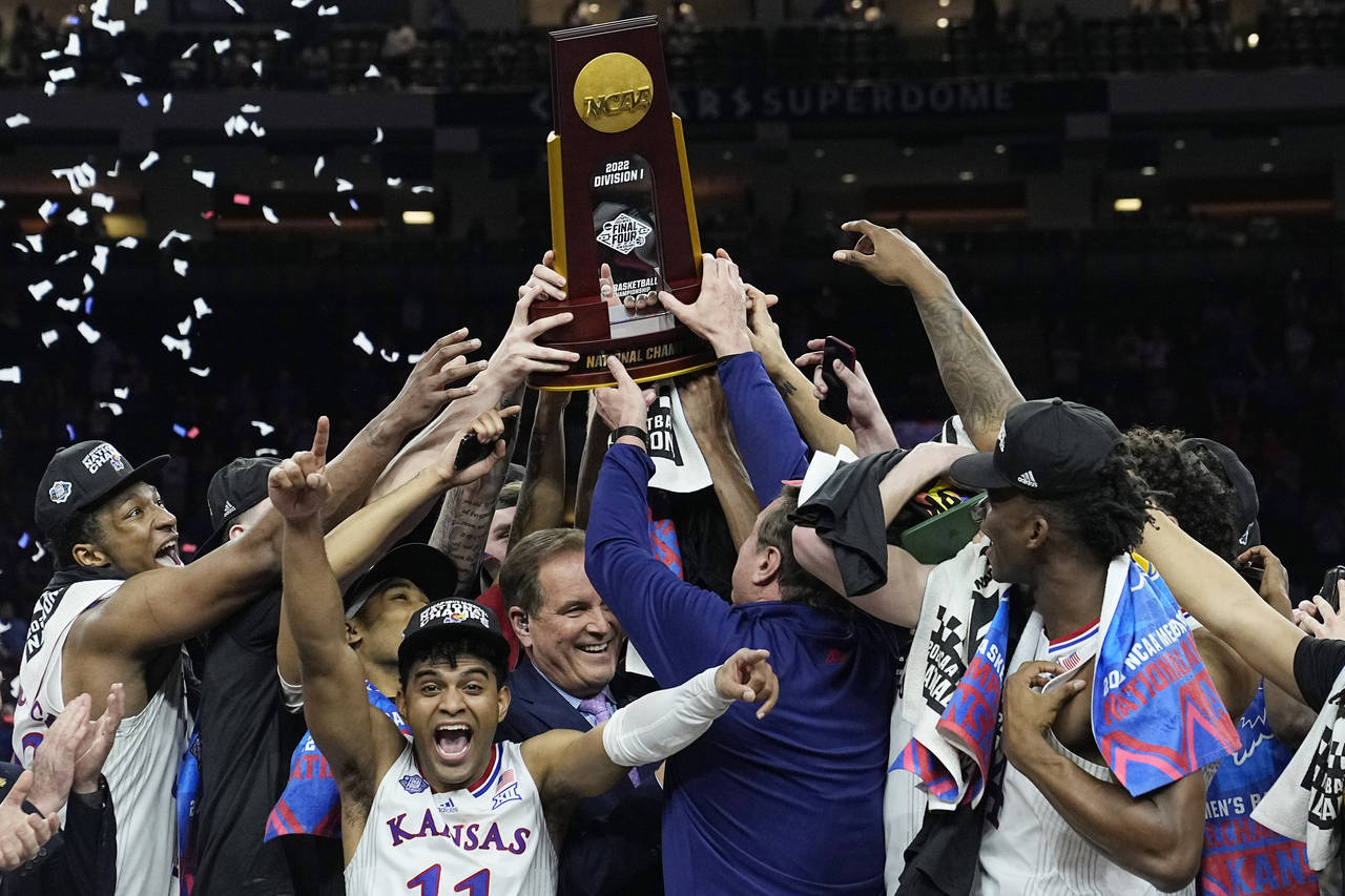 Kansas celebrates with the trophy after their win against North Carolina in a college basketball ga...