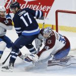 
              Colorado Avalanche goaltender Darcy Kuemper (35) saves against a shot as Avalanche's Nathan MacKinnon (29) and Winnipeg Jets' Adam Lowry (17) fight for position during second-period NHL hockey game action in Winnipeg, Manitoba, Sunday, April 24, 2022. (John Woods/The Canadian Press via AP)
            