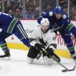 
              Vancouver Canucks' Luke Schenn (2) knocks the puck away from San Jose Sharks' Nick Bonino (13) as Vancouver's J.T. Miller (9) watches during the third period of an NHL hockey game Saturday, April 9, 2022, in Vancouver, British Columbia. (Darryl Dyck/The Canadian Press via AP)
            