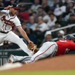 
              Washington Nationals designated hitter Nelson Cruz (23) dives back to first base to avoid being tagged out by Atlanta Braves first baseman Matt Olson (28) after hitting a single in the third inning of a baseball game Monday, April 11, 2022, in Atlanta. (AP Photo/John Bazemore)
            