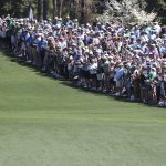 
              Una multitud observa y aplaude al cinco veces campeón del Masters Tiger Woods mientras camina en el fairway después de su salida desde el tee para iniciar una ronda de entrenamiento para el Masters en el club de golf Augusta National, en Augusta, Ga., el lunes 4 de abril de 2022. (Curtis Compton /Atlanta Journal-Constitution via AP)
            