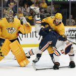 
              Edmonton Oilers' Jesse Puljujarvi (13) is checked by Nashville Predators' Jeremy Lauzon (3) as Predators goaltender Juuse Saros (74) watches the play in the first period of an NHL hockey game Thursday, April 14, 2022, in Nashville, Tenn. (AP Photo/Mark Humphrey)
            