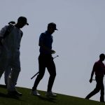 
              Tiger Woods walks down the fourth fairway with Joaquin Niemann, of Chile, and their caddies during the first round at the Masters golf tournament on Thursday, April 7, 2022, in Augusta, Ga. (AP Photo/Charlie Riedel)
            