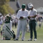 
              Rory McIlroy, of Northern Ireland, checks his course notes with his caddie on the first hole during a practice round for the Masters golf tournament on Monday, April 4, 2022, in Augusta, Ga. (AP Photo/Charlie Riedel)
            