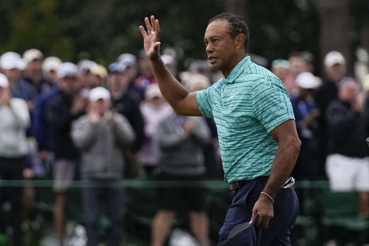 Tiger Woods waves to the gallery after putting out on the 18th green during the second round at the...