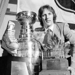 
              FILE - New York Islanders right wing Mike Bossy poses in New York with some of the spoils reaped after the Islanders defeated the Vancouver Canucks to win the Stanley Cup at the Nassau Coliseum in Uniondale, N.Y., May 20, 1982. Bossy scored two goals in the game and finished the playoffs with 17, earning the Conn Smythe MVP trophy at right and the Sport Magazine MVP trophy, left, At center is the Stanley Cup. Bossy, one of hockey’s most prolific goal-scorers and a star for the New York Islanders during their 1980s dynasty, died Thursday, April 14, 2022, after a battle with lung cancer. He was 65. (AP Photo/Marty Lederhandler, File)
            