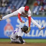 
              Philadelphia Phillies' Johan Camargo, top, leaps to avoid Colorado Rockies' Ryan McMahon, bottom, after turning a double play on a ball hit by Rockies' Brendan Rodgers during the seventh inning of a baseball game, Monday, April 25, 2022, in Philadelphia. (AP Photo/Derik Hamilton)
            