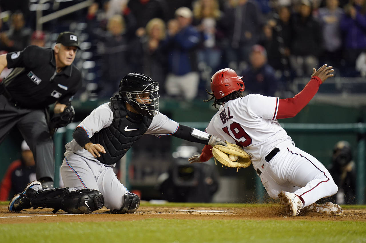 Miami Marlins catcher Jacob Stallings, left, tags out Washington Nationals' Josh Bell at home plate...