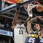 
              San Antonio Spurs guard Joshua Primo, left, hangs from the rim after a dunk next to Denver Nuggets guard Austin Rivers during the first half of an NBA basketball game Tuesday, April 5, 2022, in Denver. (AP Photo/David Zalubowski)
            