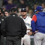 
              Seattle Mariners acting manager Kristopher Negron, second from right, talks with umpires at home plate before a baseball game against the Texas Rangers, Wednesday, April 20, 2022, in Seattle. Negron was in the position due to manger Scott Servais testing positive for COVID-19. (AP Photo/Ted S. Warren)
            