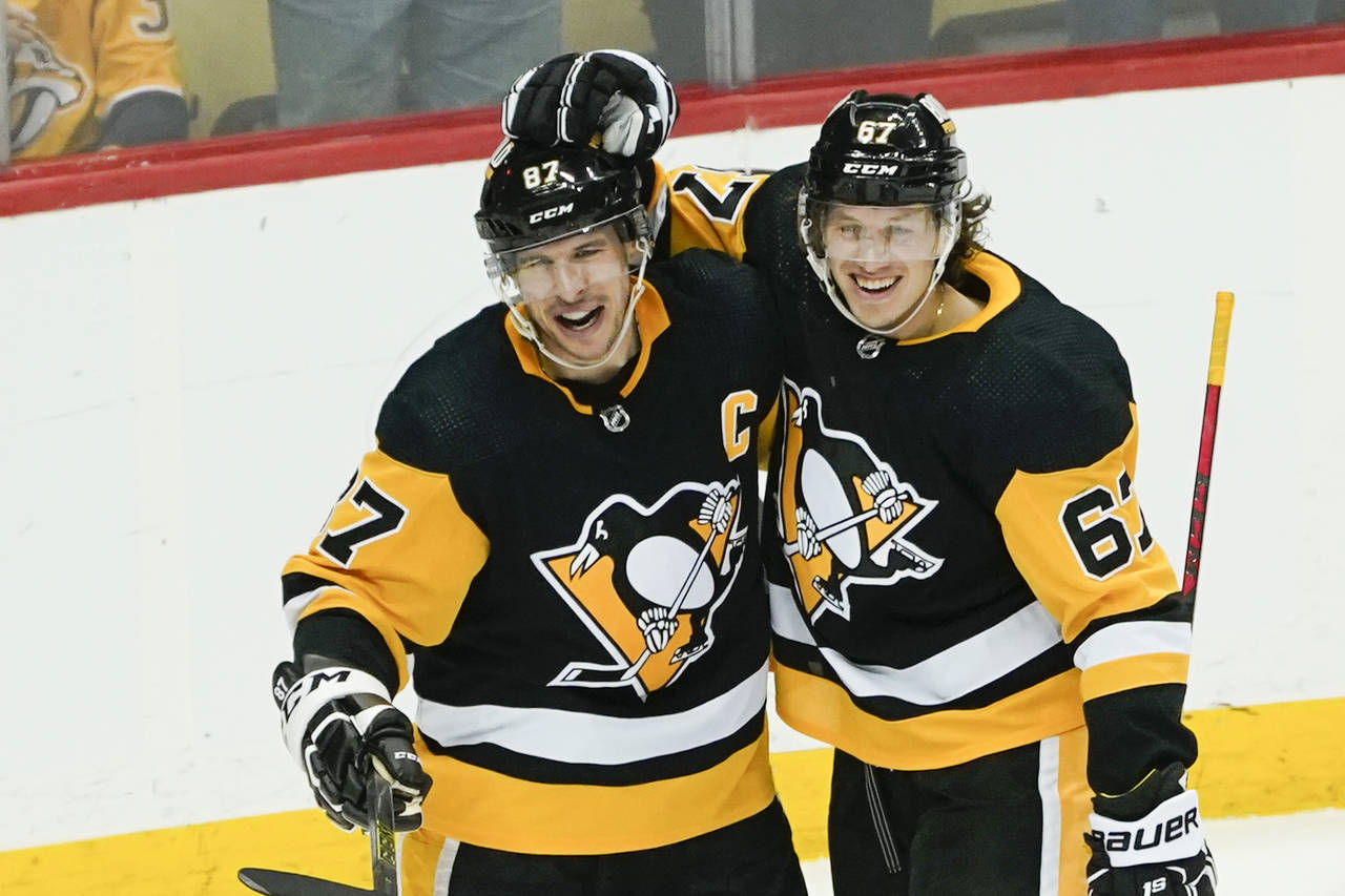 Pittsburgh Penguins' Sidney Crosby, left, celebrates with Rickard Rakell (67) after scoring the gam...