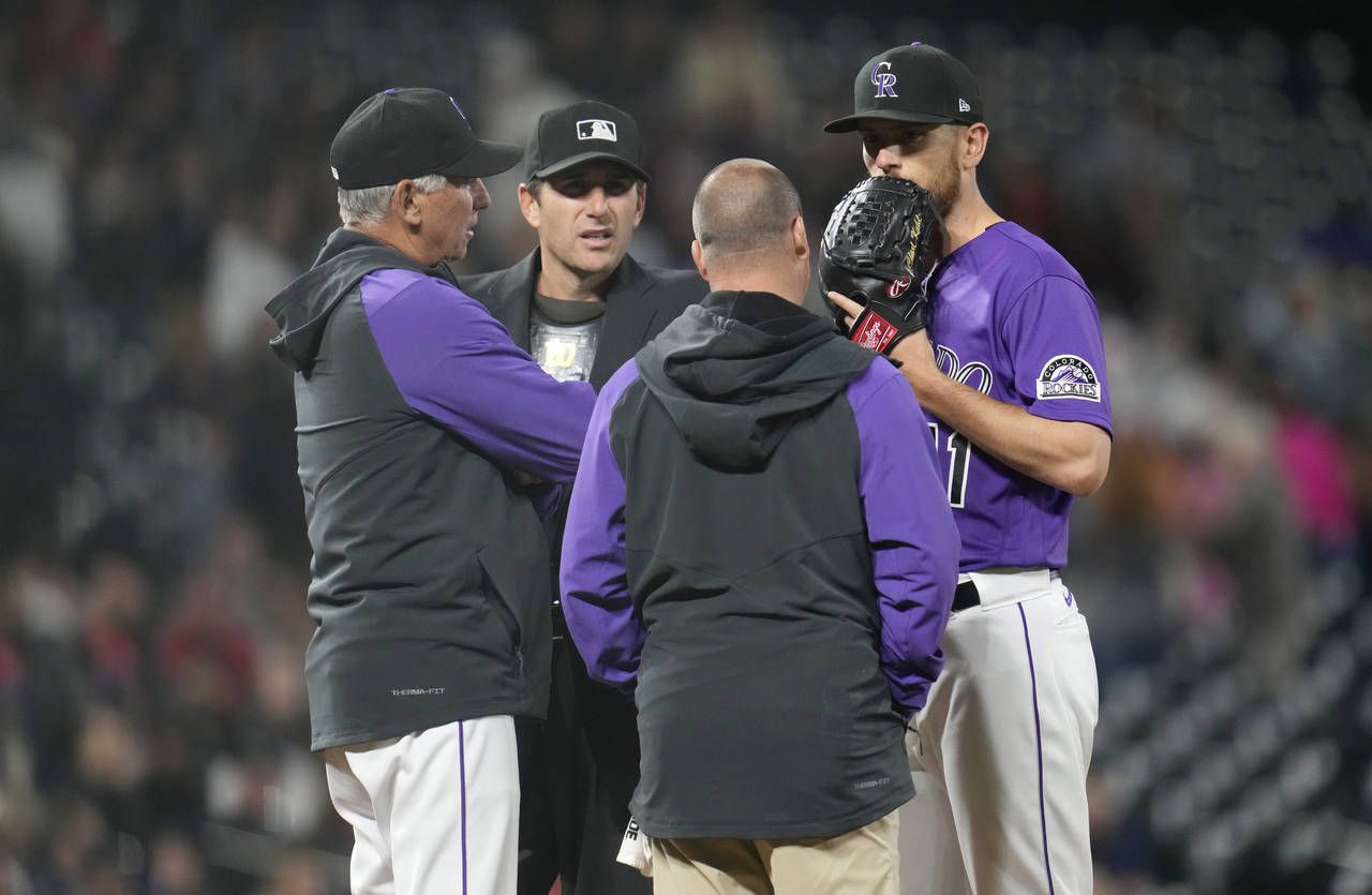 Colorado Rockies starting pitcher Chad Kuhl, right, confers with trainer Heath Townsend, second fro...