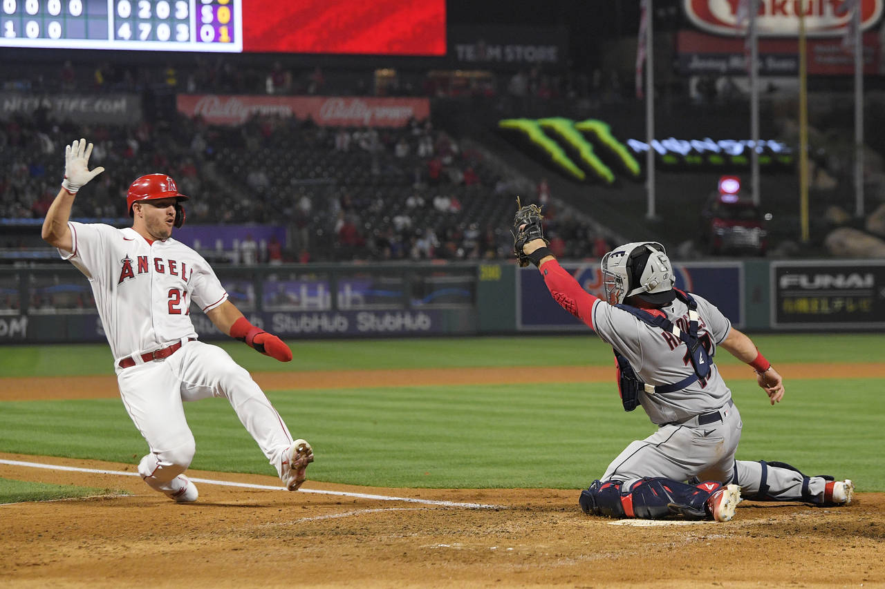Los Angeles Angels' Mike Trout, left, slides before being tagged out at home by Cleveland Guardians...