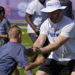 
              Aidan Hutchinson, right, works with young football players during a community event ahead of the NFL draft Wednesday, April 27, 2022, in Las Vegas. (AP Photo/John Locher)
            