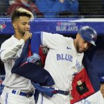 
              Toronto Blue Jays' Lourdes Gurriel Jr., left, puts the team's home run jacket on teammate George Springer after Springer hit a solo home run against the Texas Rangers during a baseball game in Toronto, Sunday, April 10, 2022. (Frank Gunn/The Canadian Press via AP)
            