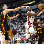 
              Miami Heat forward Jimmy Butler (22) goes to the basket as Atlanta Hawks guard Bogdan Bogdanovic, left, and forward John Collins (20) defend during the first half of Game 1 of an NBA basketball first-round playoff series, Sunday, April 17, 2022, in Miami. (AP Photo/Lynne Sladky)
            