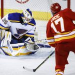 
              St. Louis Blues goalie Ville Husso, left, stops a shot by Calgary Flames' Milan Lucic during second-period NHL hockey game action in Calgary, Alberta, Saturday, April 2, 2022. (Jeff McIntosh/The Canadian Press via AP)
            