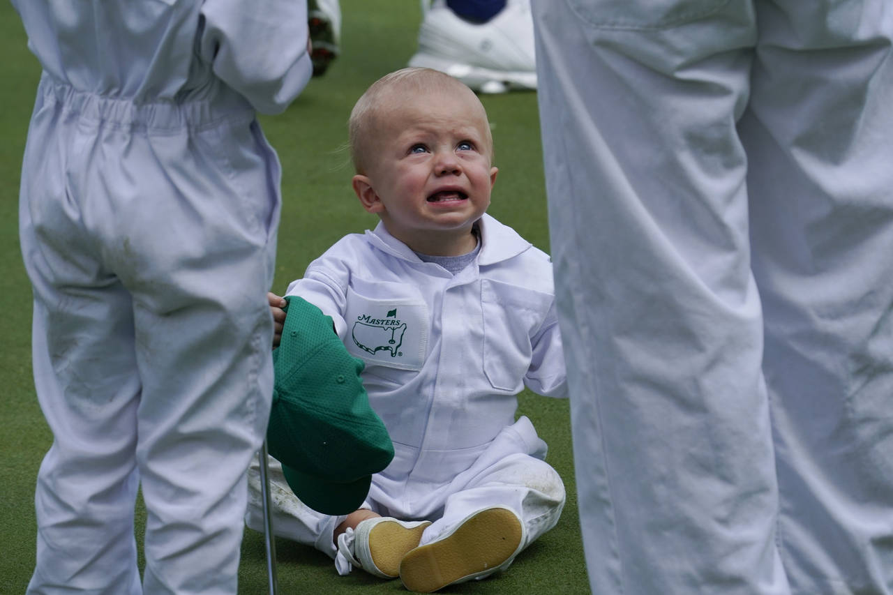 Mackenzie Hughes, of Canada's son Cohen sits on the night green during the Par 3 contest at the Mas...