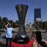 
              A man poses for a photo next to a replica of the Europa Conference League trophy ahead of the final between Roma and Feyenoord in Tirana, Albania, Wednesday, May 25, 2022. (AP Photo/Thanassis Stavrakis)
            