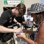 
              Callum Ilott, of England, signs an autograph for a fan during practice for the Indianapolis 500 auto race at Indianapolis Motor Speedway, Friday, May 20, 2022, in Indianapolis. (AP Photo/Darron Cummings)
            