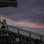 
              Fans look over the rail from the club level of Coors Field to watch the setting sun illuminate clouds, during the a baseball game between the Colorado Rockies and the Kansas City Royals on Saturday, May 14, 2022, in Denver. (AP Photo/David Zalubowski)
            