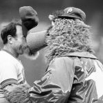 
              FILE - New York Mets coach Joe Pignatano's cap stands on end as he is "kissed" by the Philadelphia Phillies mascot, the Philly Phanatic, before a baseball game in Philadelphia, June 4, 1981. Pignatano, who made his major league debut with the Brooklyn Dodgers in 1957 and later was a coach for the Mets, died Monday, May 23, 2022, in Naples, Fla. (AP Photo/Rusty Kennedy, File)
            