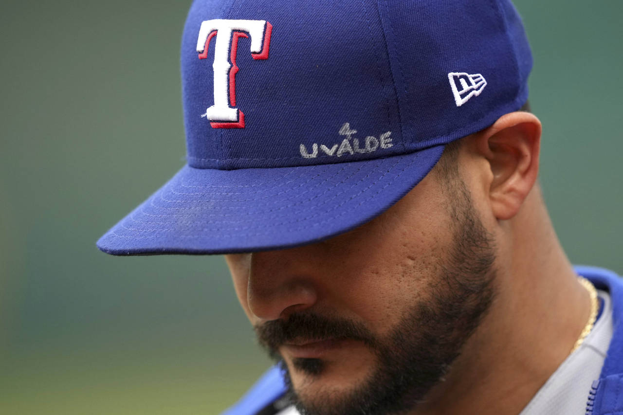 Texas Rangers' Martin Perez walks to the dugout with an inscription on his hat dedicated to the vic...
