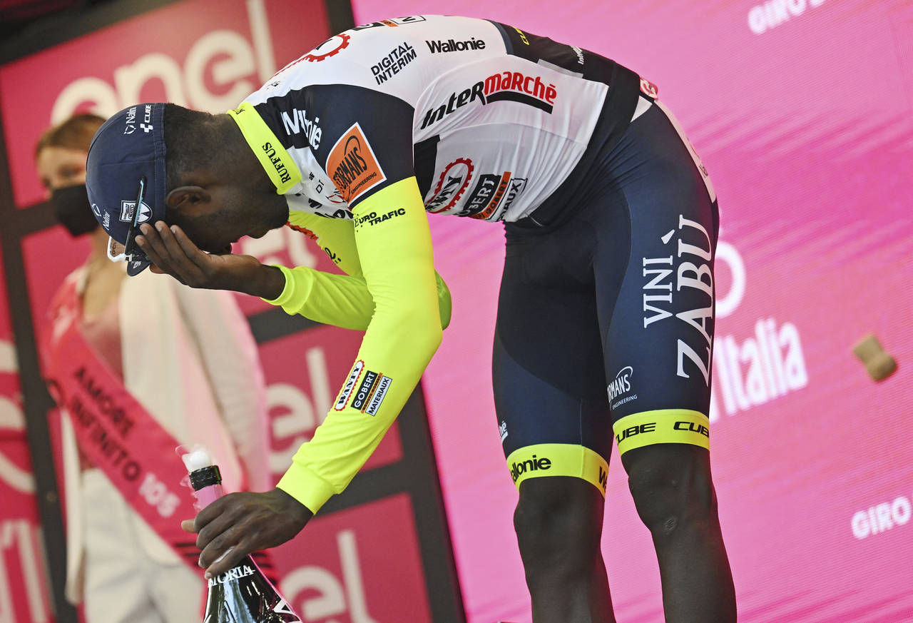 Eritrea's Biniam Girmay touches his eye after spraying sparkling wine on the podium to celebrate wi...