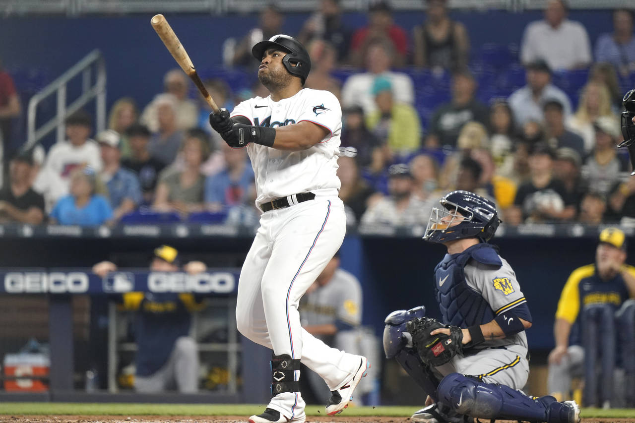 Miami Marlins' Jesus Aguilar, left, watches his solo home run next to Milwaukee Brewers catcher Vic...