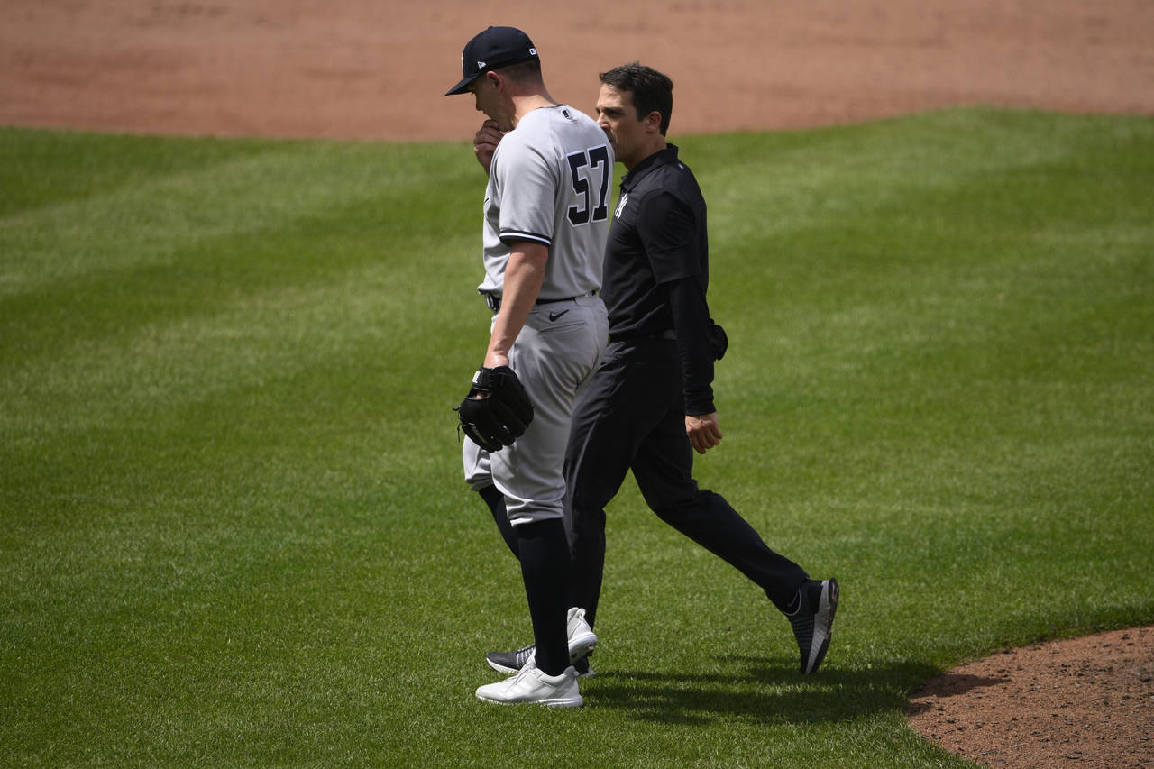 New York Yankees relief pitcher Chad Green (57) walks off the field with a trainer during the sixth...
