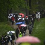 
              Fans with umbrellas walk through the rain along the seventh fairway during the third round of the Wells Fargo Championship golf tournament, Saturday, May 7, 2022, at TPC Potomac at Avenel Farm golf club in Potomac, Md. (AP Photo/Nick Wass)
            