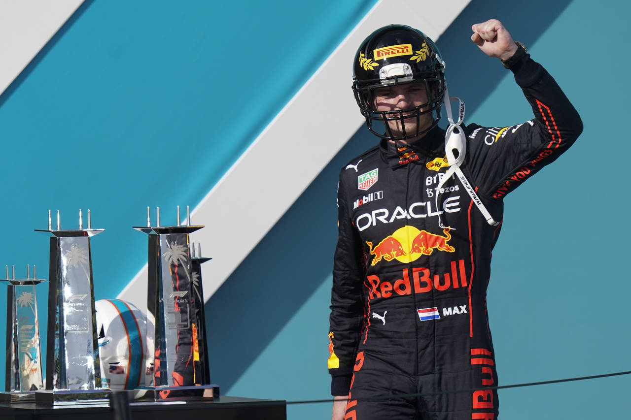 Red Bull driver Max Verstappen of the Netherlands takes the stage wearing a football helmet after w...