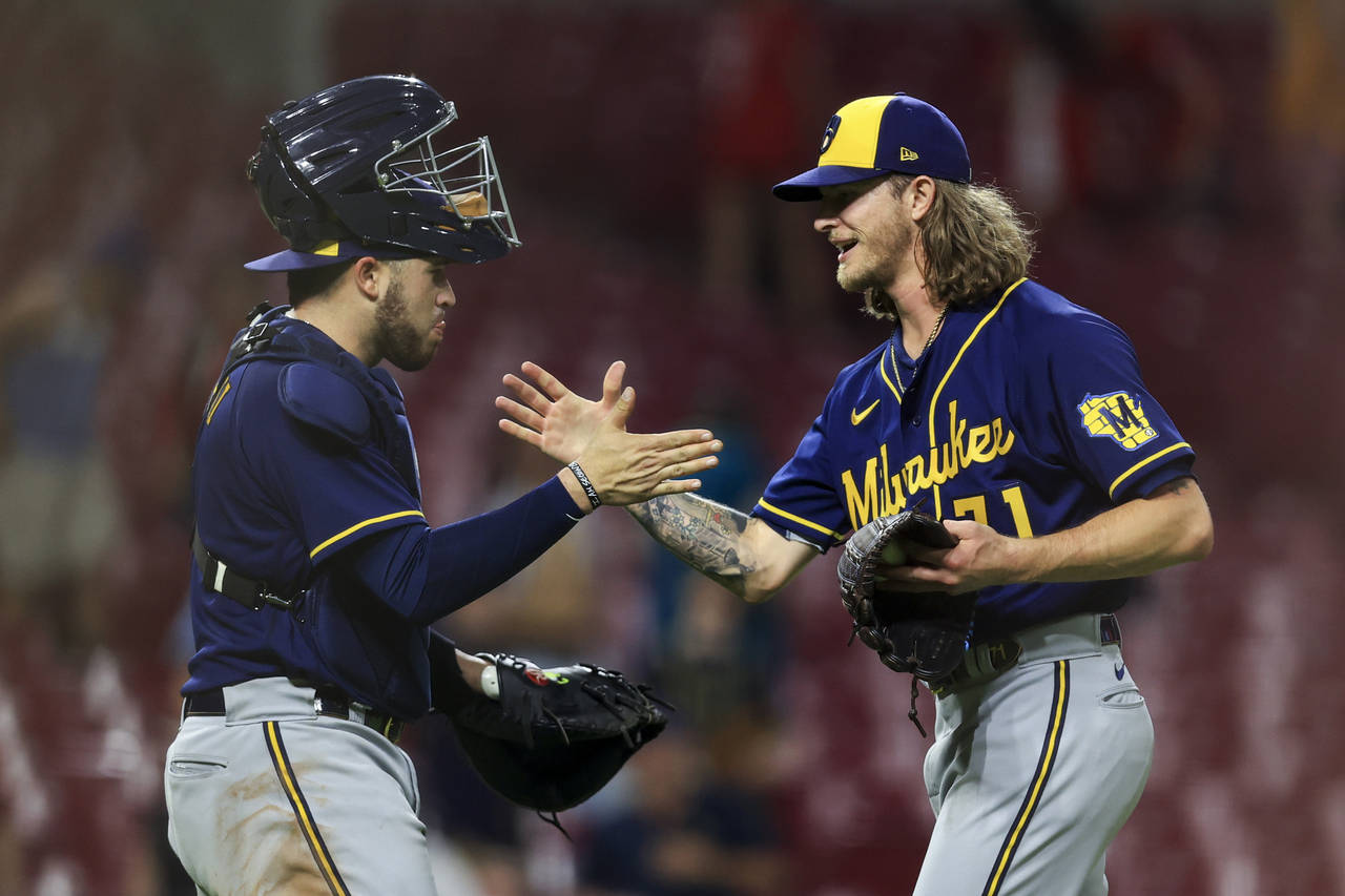 Milwaukee Brewers' Victor Caratini, left, high-fives Josh Hader after the final out a baseball game...