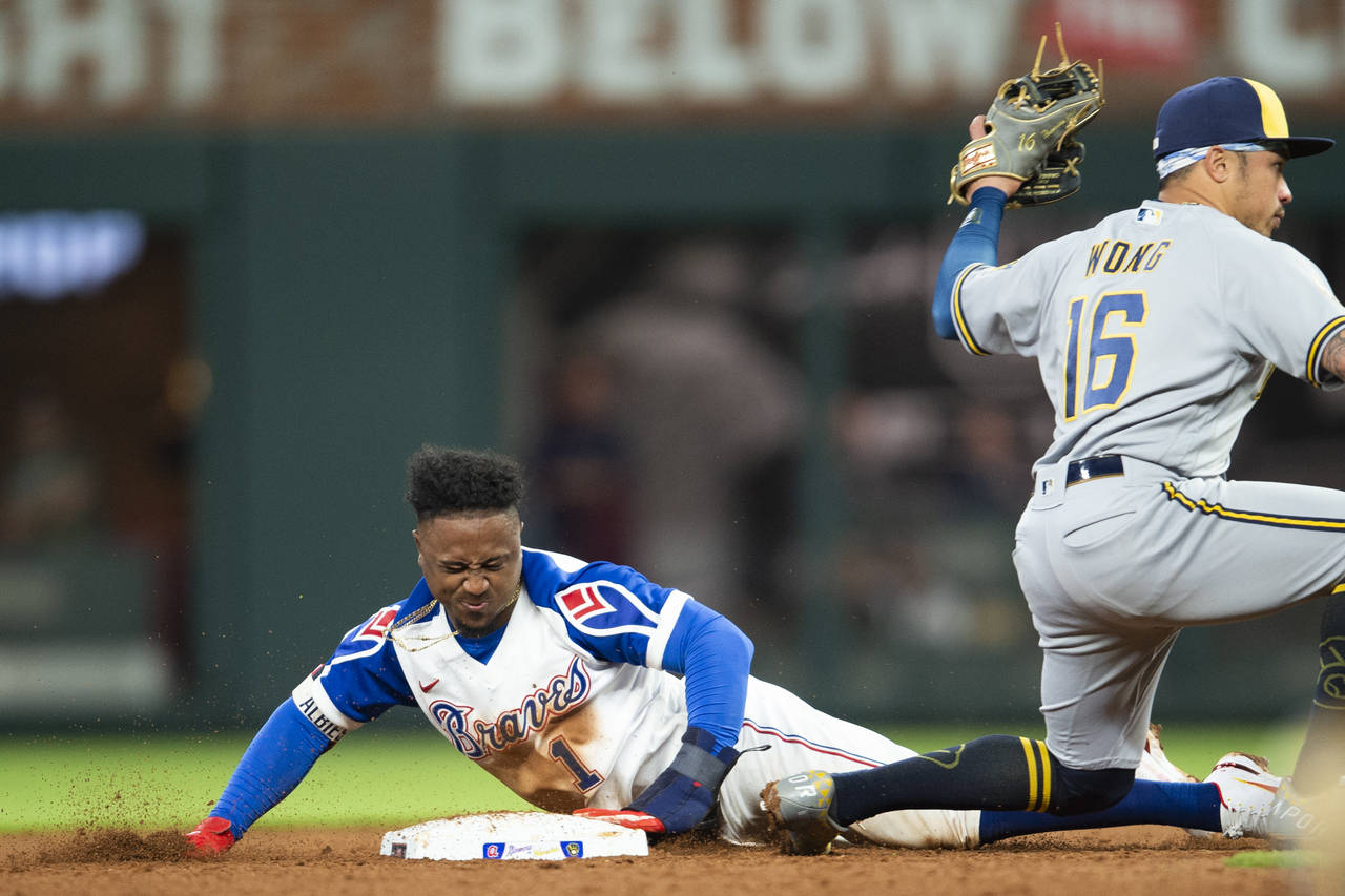 Milwaukee Brewers second baseman Kolten Wong (16) tags out Atlanta Braves' Ozzie Albies (1) in the ...