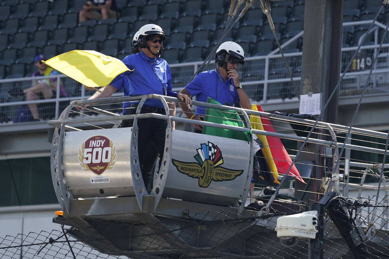 An official hold the yellow flag as it blows in the wind during practice for the Indianapolis 500 a...