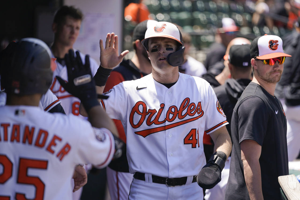 Baltimore Orioles' Tyler Nevin, center, is greeted in the dugout after scoring on a single by Jorge...