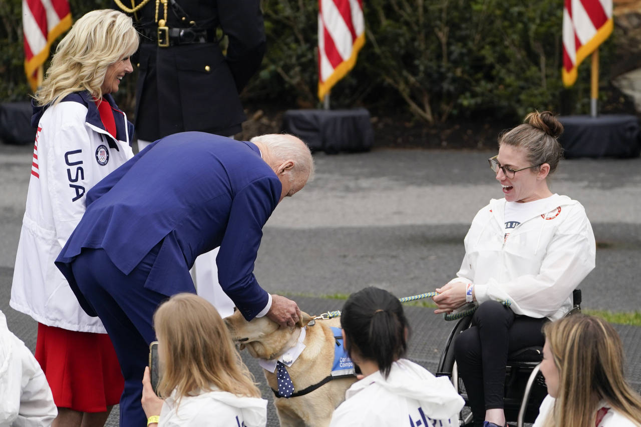 President Joe Biden and first lady Jill Biden stop to pet a service dog as they arrive for an event...