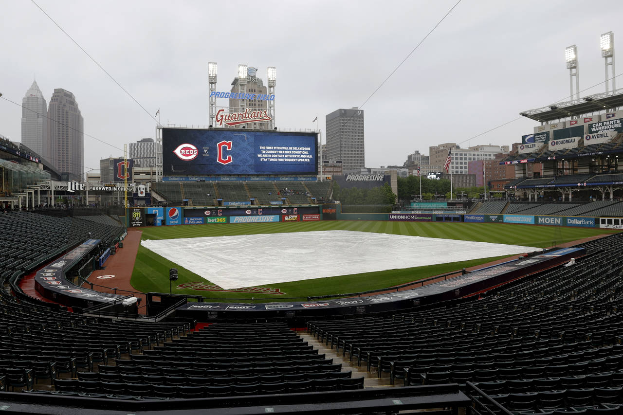 A tarp covers the infield as the start of a baseball game between the Cincinnati Reds and the Cleve...