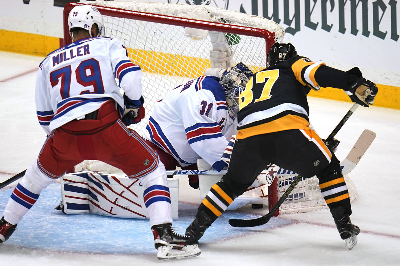 Pittsburgh Penguins' Sidney Crosby (87) pokes the puck under the pad of New York Rangers goaltender...