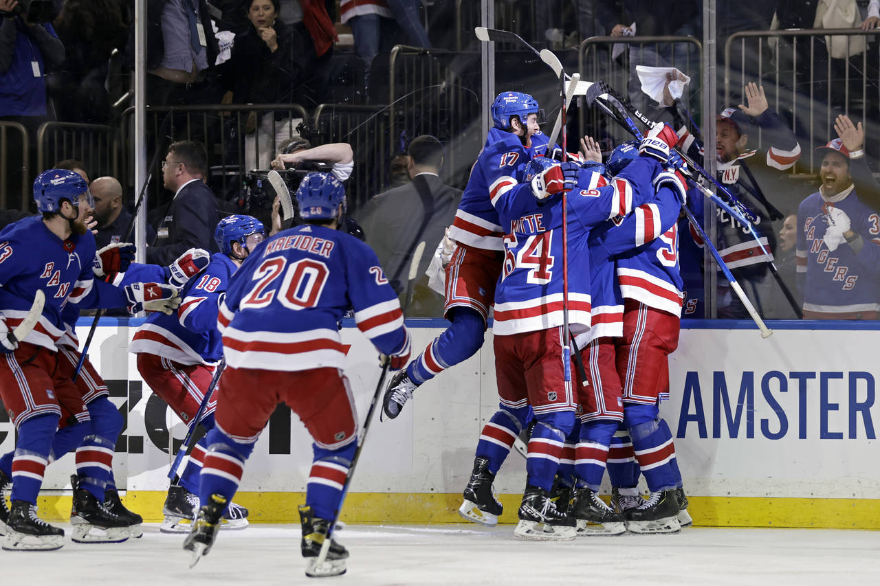 New York Rangers left wing Artemi Panarin is mobbed by teammates after scoring the game winning goa...