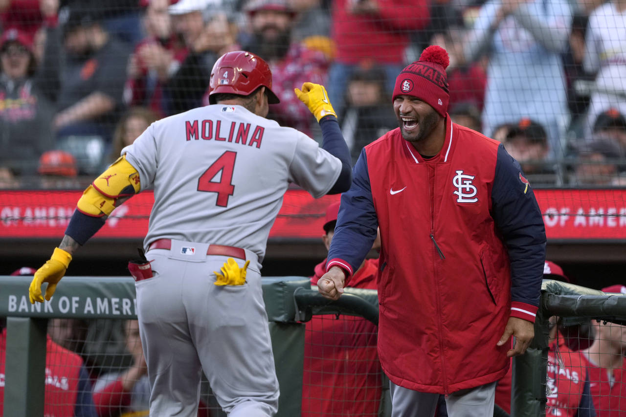 St. Louis Cardinals' Yadier Molina (4) is congratulated by Albert Pujols, right, after hitting a so...